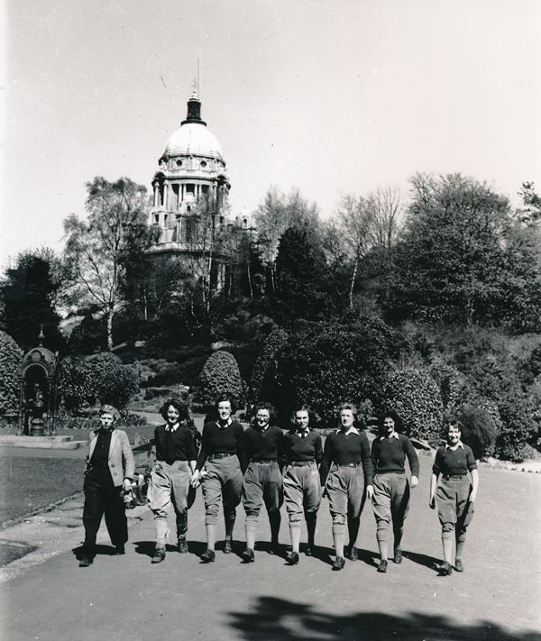 Photo of a group of land girls in trousers and pullovers walking along in front of Lancaster's Ashton Memorial.